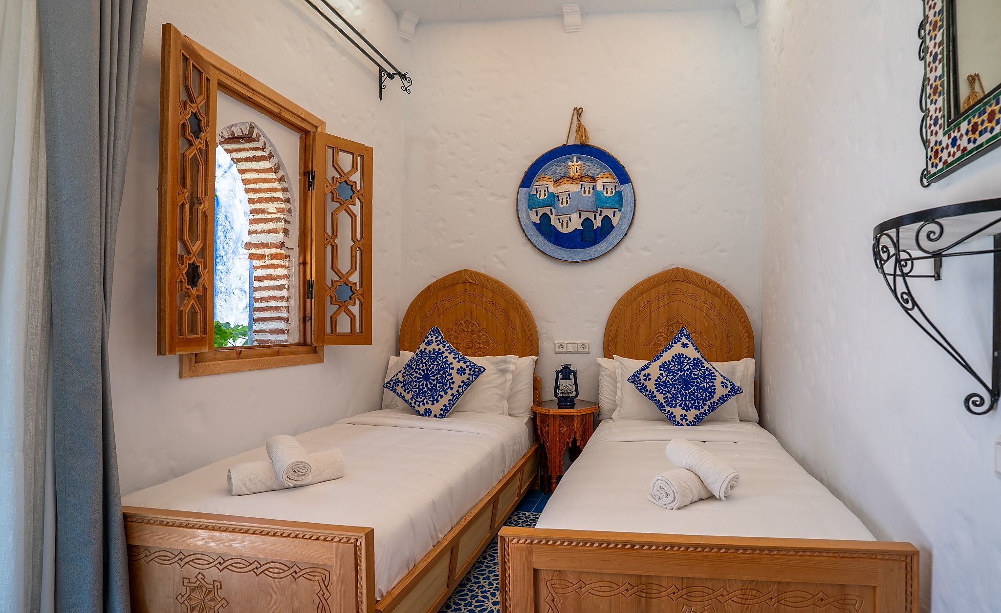 Una habitación con dos camas, una lámpara de pared y un plato decorativo.