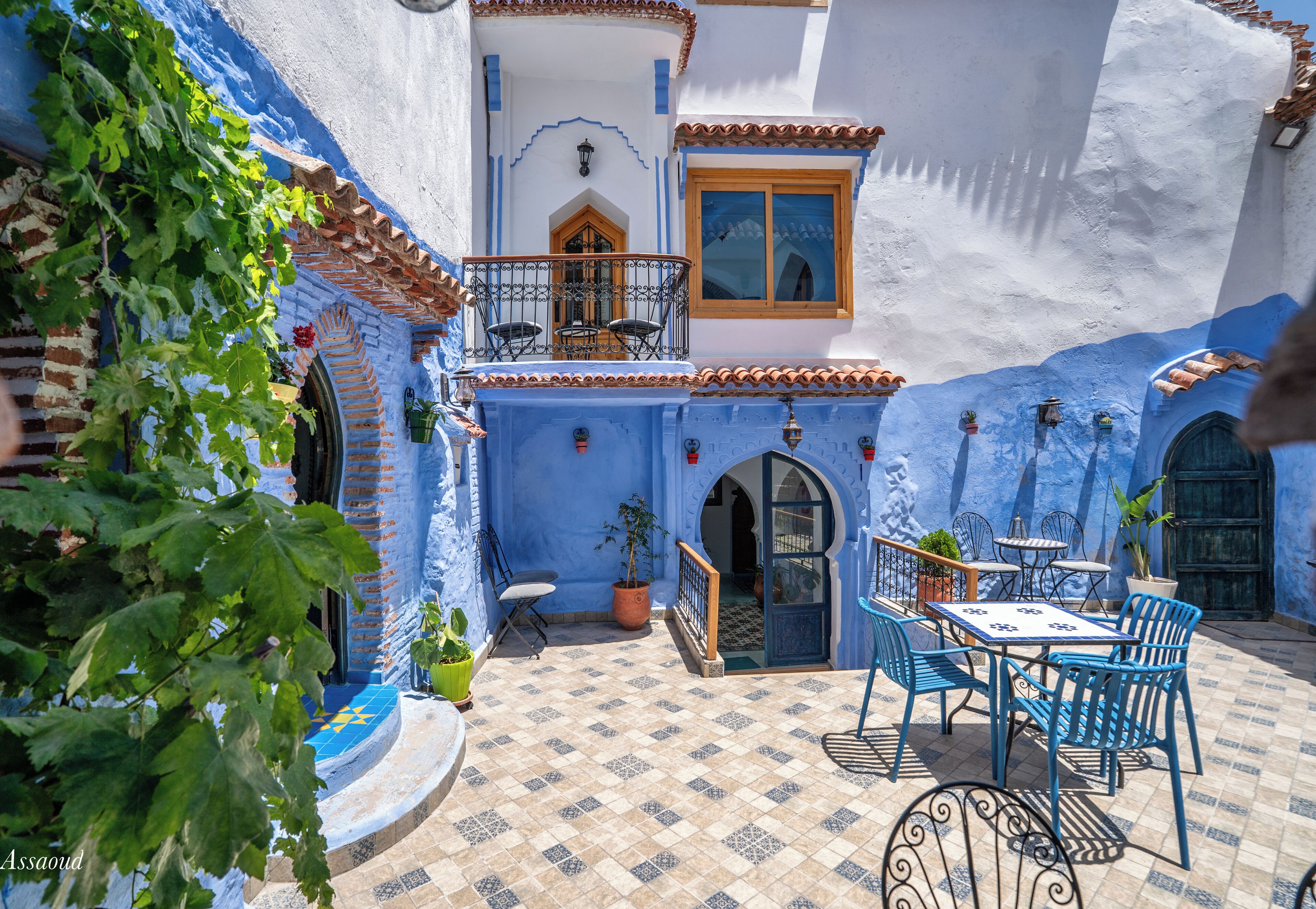 Une cour avec des murs bleus, un sol carrelé et du mobilier d’extérieur.
