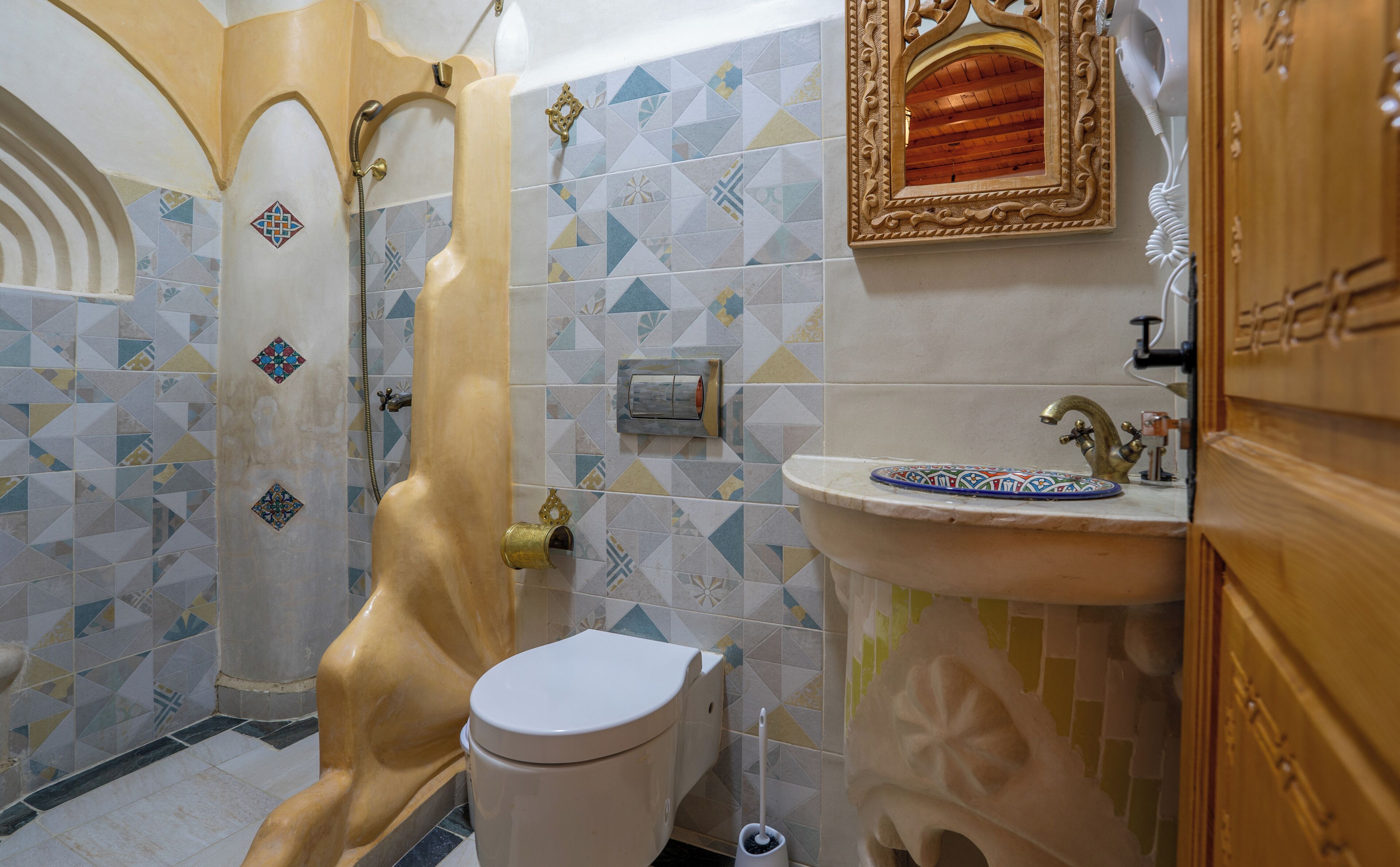 Ein Badezimmer mit Dusche, Toilette, Waschbecken und dekorativen Fliesen.