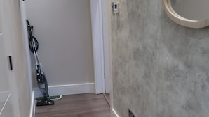 A hallway with a wooden floor, a vacuum cleaner, and a wall-mounted air conditioning unit.