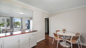A modern kitchen with white cabinets, a wooden countertop, and a dining area with a white table and wicker chairs.