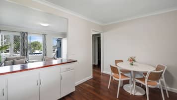 A modern kitchen with white cabinets, a wooden countertop, and a dining area with a white table and wicker chairs.