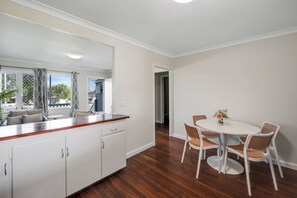 A modern kitchen with white cabinets, a wooden countertop, and a dining area with a white table and wicker chairs.