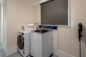 A laundry room with a washing machine, a dryer, a sink, and a mop.