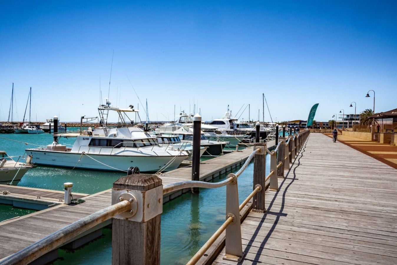 A marina with docked boats and a wooden walkway.