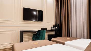 A hotel room with two beds, a TV, a desk, a chair, and a window with curtains.