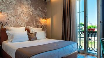 Ein Schlafzimmer mit einem großen Bett, Blick ins Freie durch eine Schiebetür und einer strukturierten Wand.