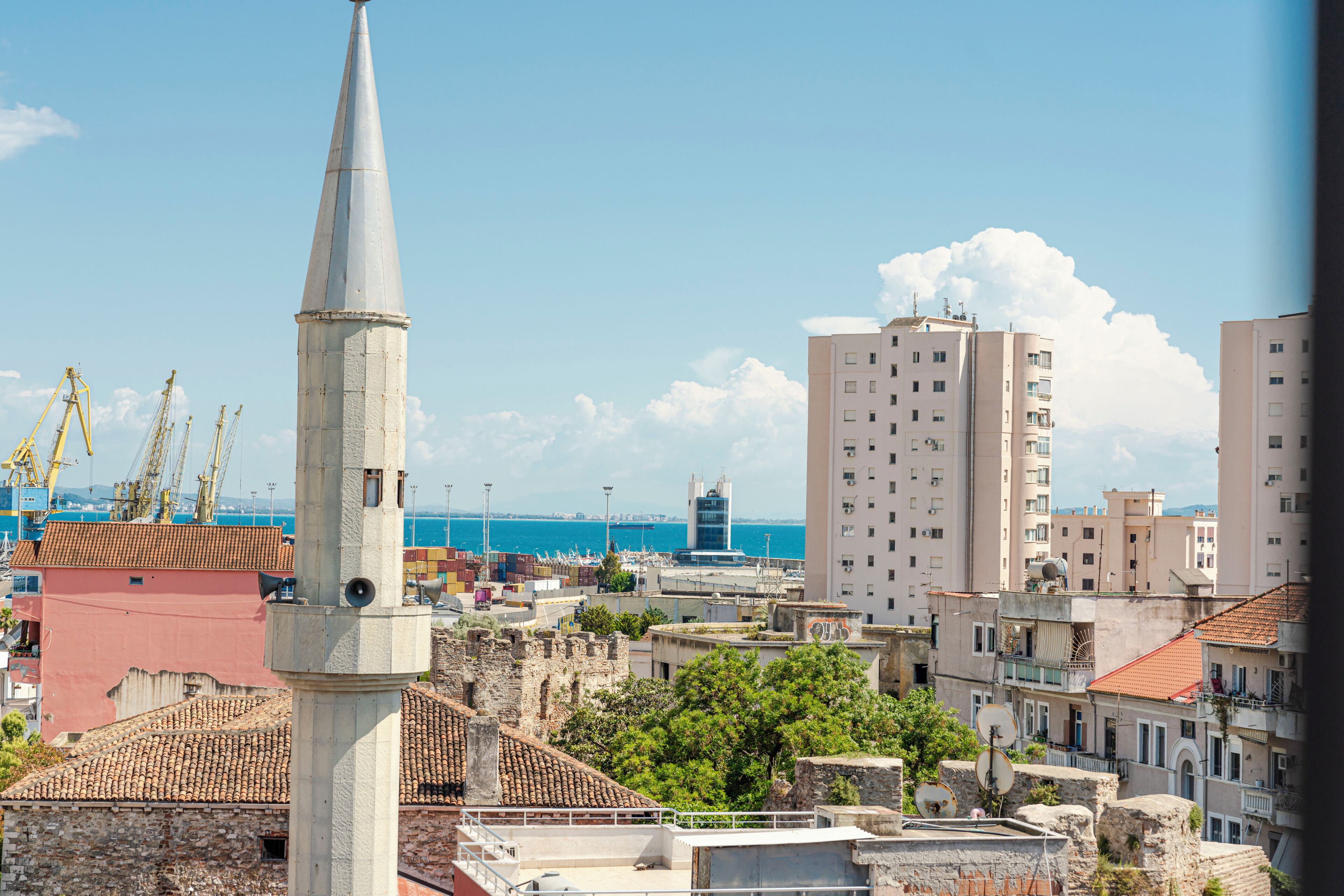 Eine Küstenstadtlandschaft mit einem markanten Turm, Wohngebäuden und freiem Blick auf das Meer.