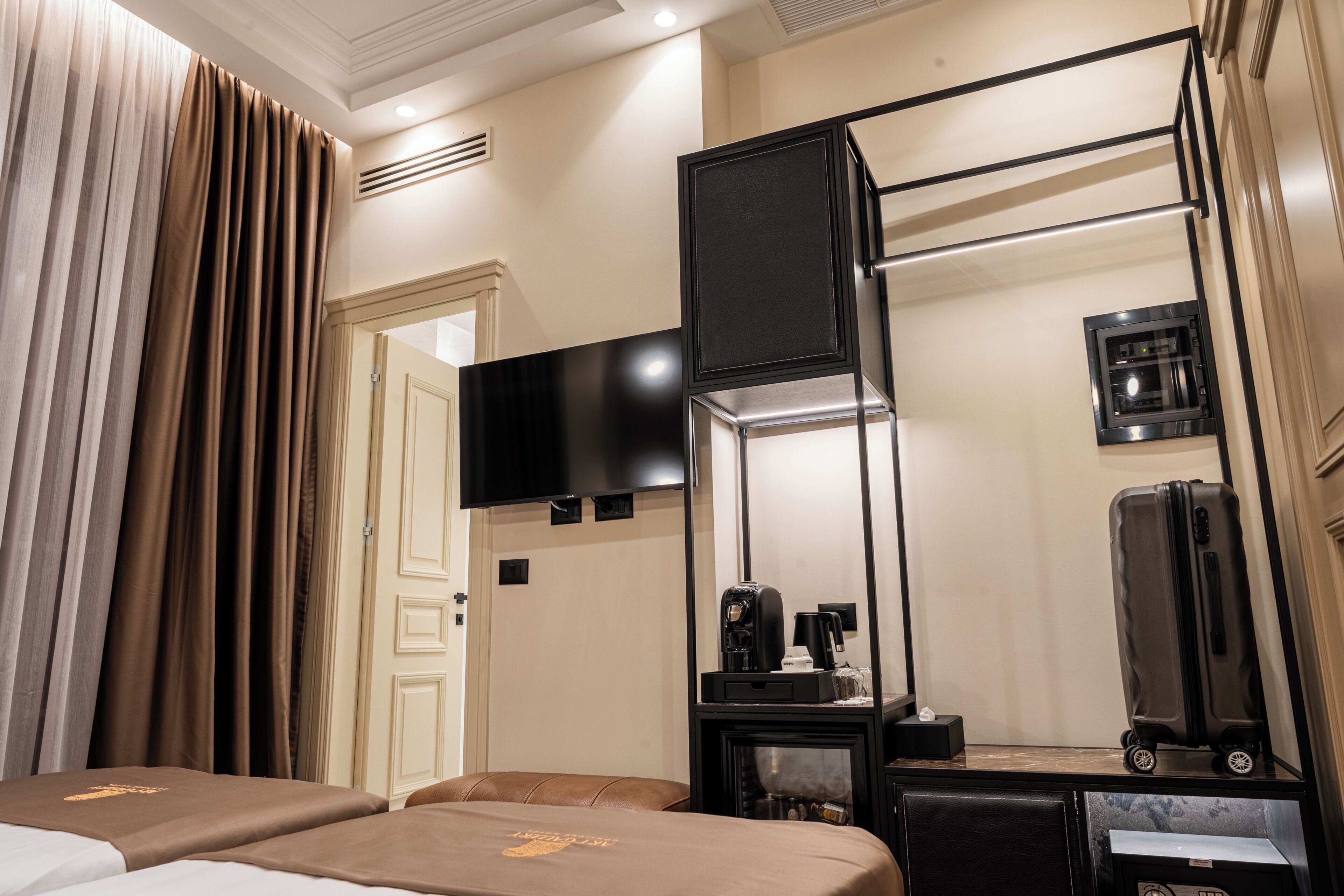 Ein Hotelzimmer mit einem Bett, einem Schreibtisch mit Flachbildfernseher, einer Kaffeemaschine und einem Koffer.
