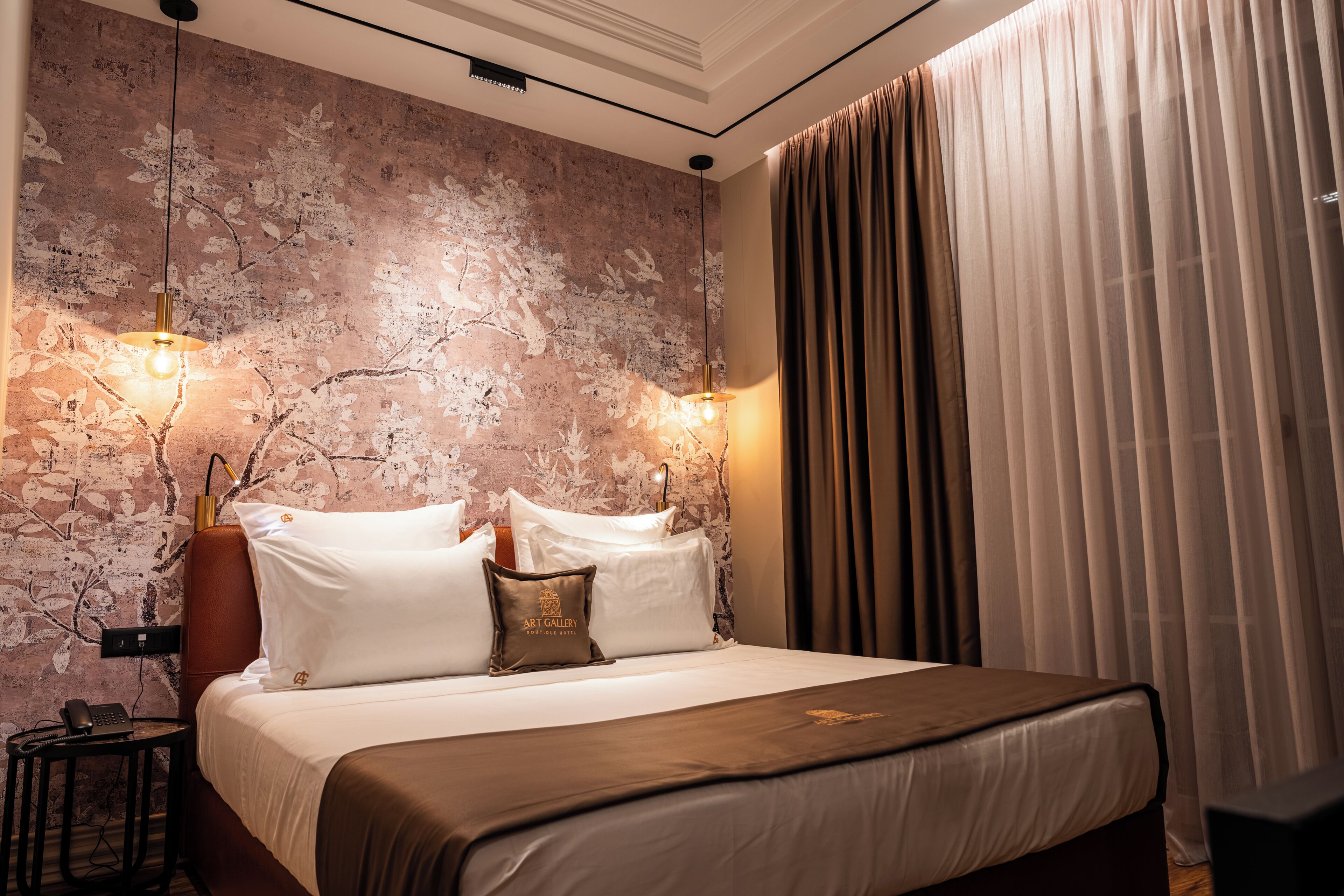 A hotel room with a bed, a wall-mounted telephone, and a lamp.