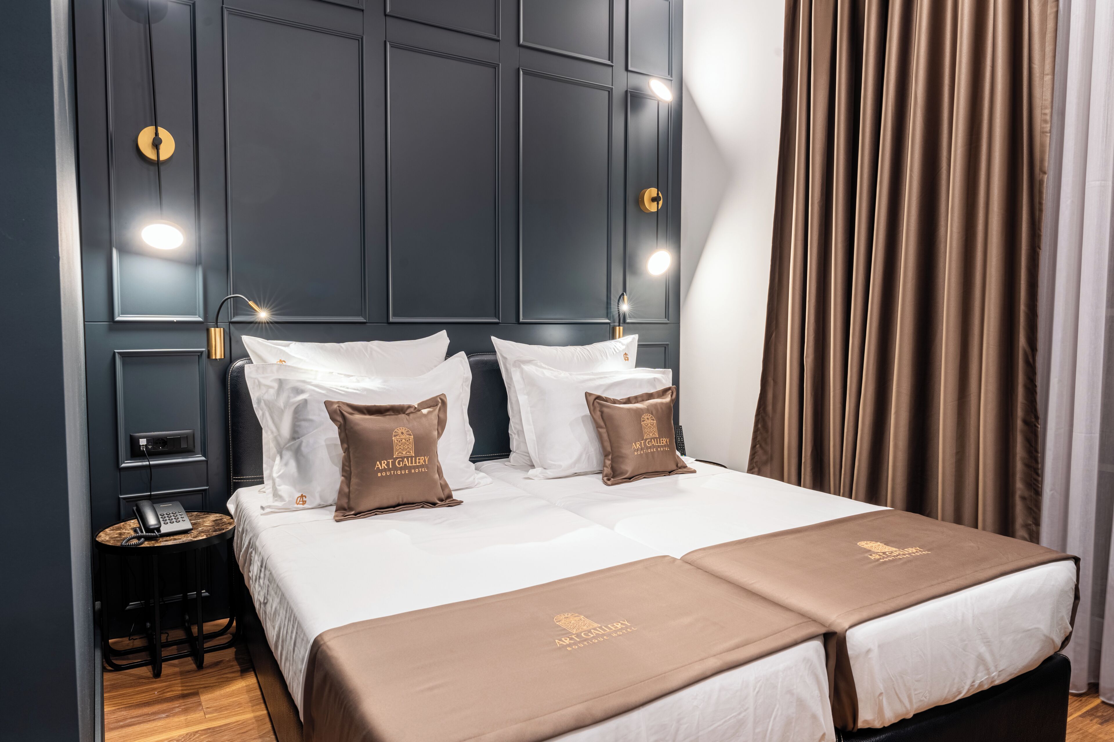 A hotel room with a large bed, two bedside tables, a telephone, and a wall-mounted light fixture.