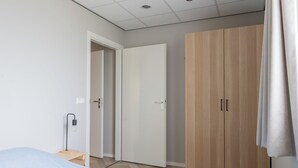 Une chambre à coucher avec un lit, une armoire et une table de chevet.