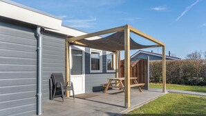 Un espace extérieur aménagé avec une pergola en bois, un barbecue et une table de pique-nique.