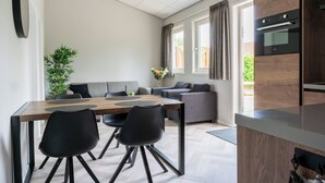 Une cuisine moderne dotée d’un four encastré et d’un coin repas avec une table en bois et des chaises noires.