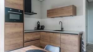 Une cuisine moderne avec des meubles en bois, un four encastré, une machine à café et un évier.