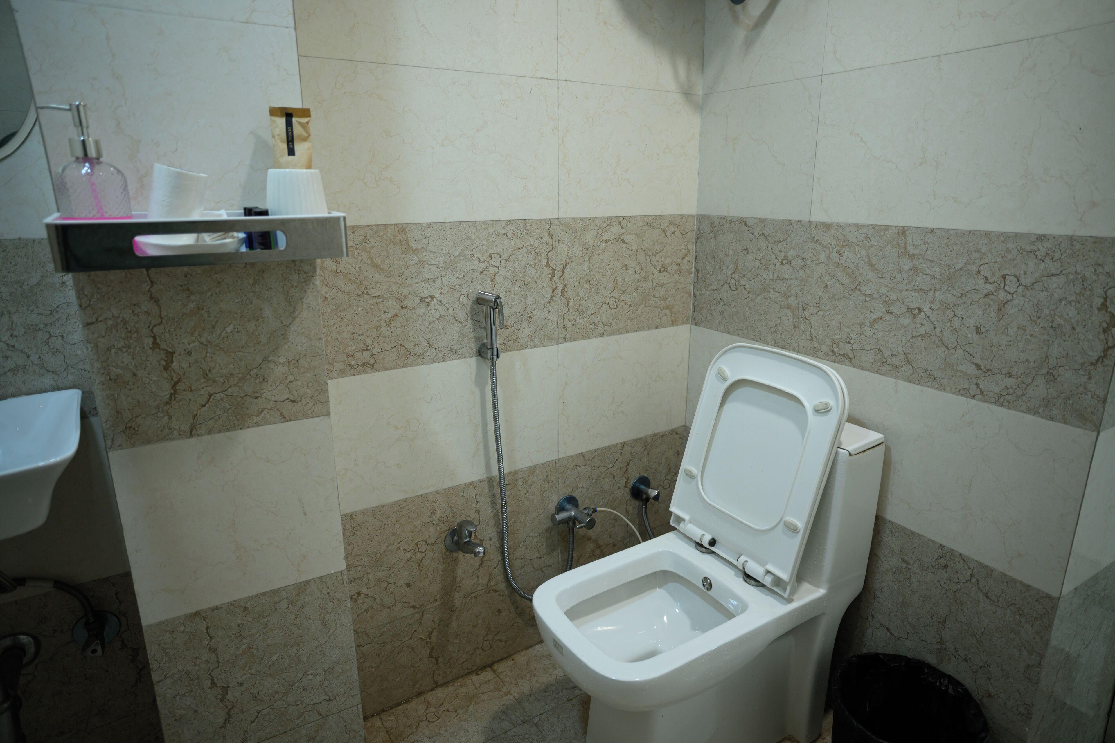 Un bagno con il water, un lavabo, una doccia e uno scaffale con articoli da toilette.