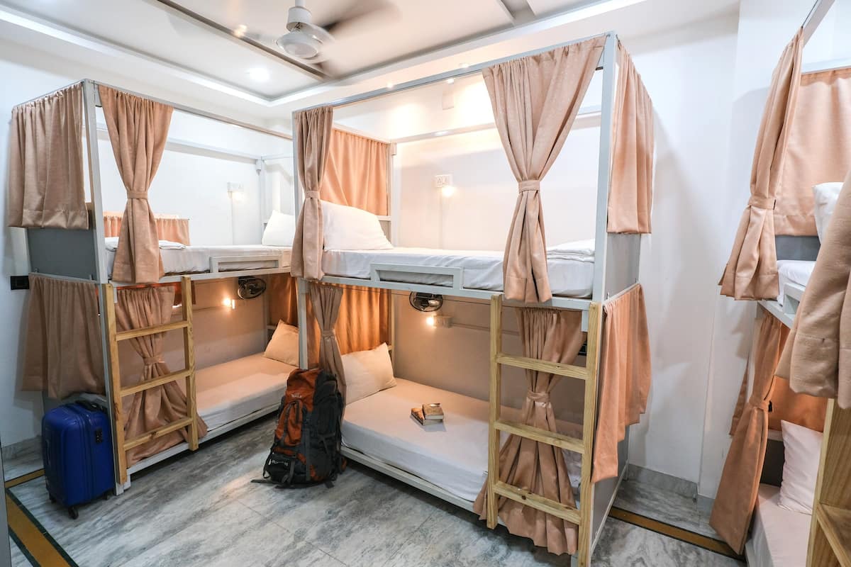 A bunk room with two beds, each with a canopy, a small table, and a suitcase.
