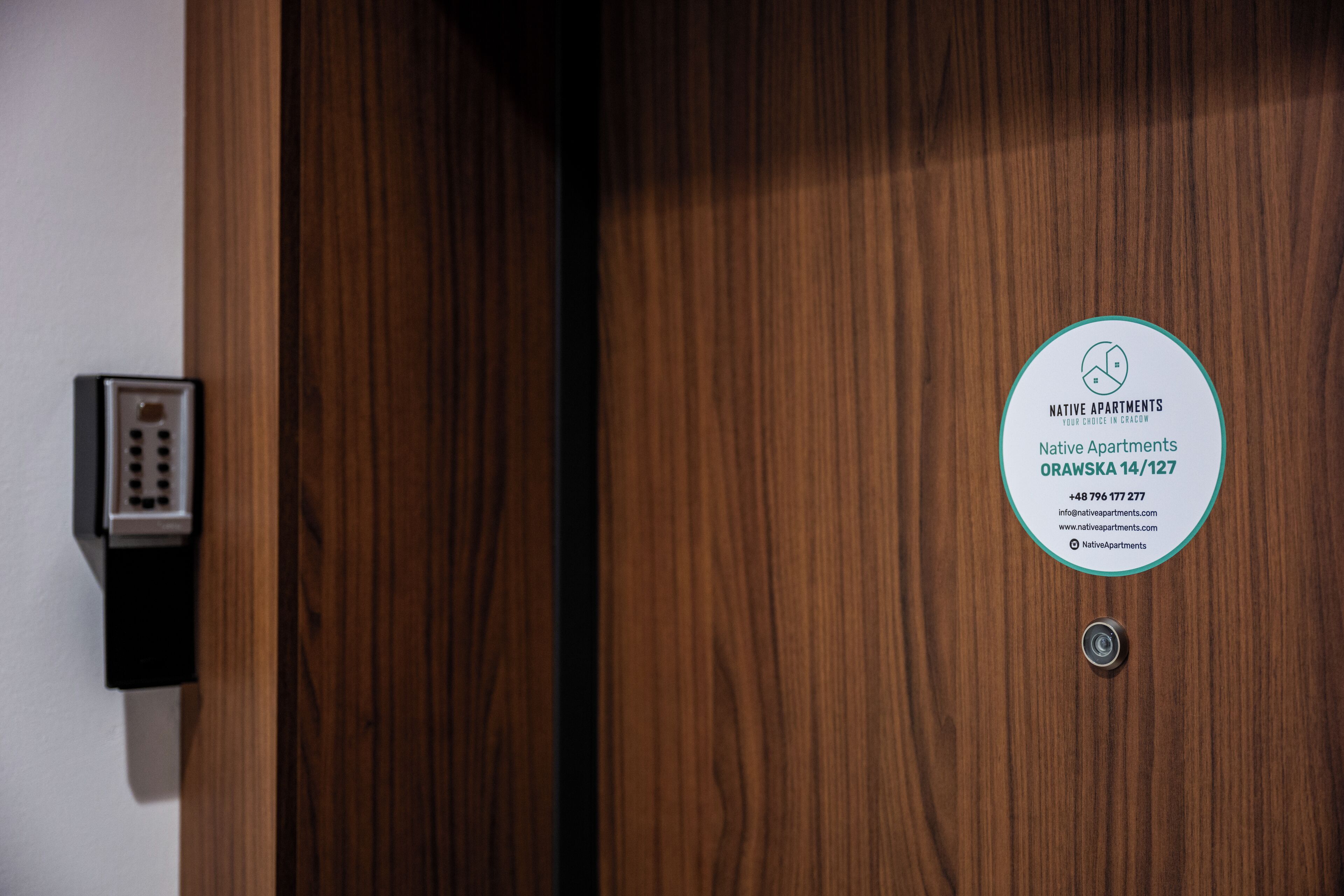 Une porte en bois sur laquelle est apposée une enseigne circulaire indiquant « Appartements pour autochtones » et fournissant les coordonnées.