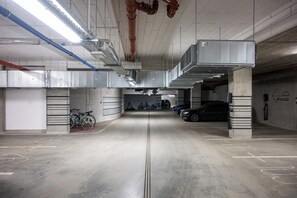 Un parking intérieur avec des planchers en béton, des emplacements de stationnement délimités et un éclairage au plafond.