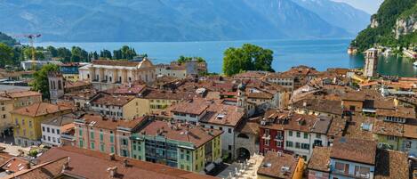 A coastal town with historic buildings, a waterfront, and mountains in the background.