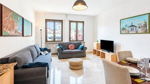 Un salon moderne comprenant un canapé, un téléviseur et un coin repas avec une table et des chaises.