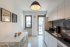 A modern kitchen with white cabinets, a black countertop, and a hanging light fixture. - Casa Lucia in Riva Town (Riva del Garda)