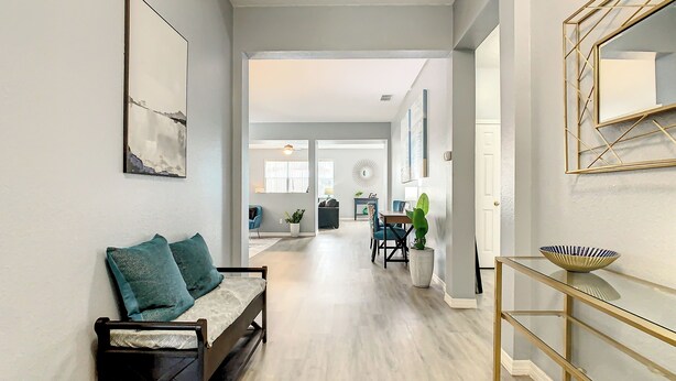 Un salon moderne avec un canapé, un coin repas comprenant une table et des chaises, et un couloir menant à une autre pièce.
