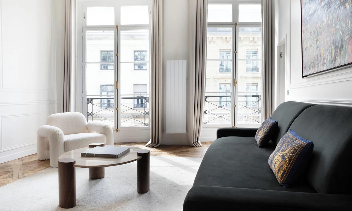 Ein modernes Wohnzimmer mit einer schwarzen Couch, einem weißen Sessel und einem runden Couchtisch.
