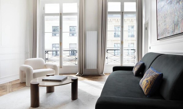 A modern living room with a black sofa, white armchair, and a round coffee table.