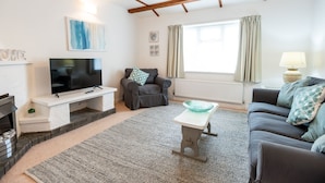 A living room with a TV, sofa, and a fireplace. - Minffordd Cottage, Moelfre - sleeps 4 guests  in 2 bedrooms (Moelfre)