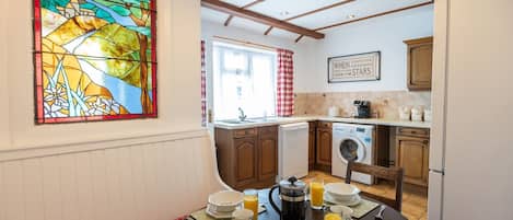 A cozy kitchen with wooden cabinets, a dining table set for breakfast, and a stained glass window.