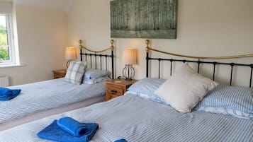 Habitación doble con dos camas, cada una con cabecero, mesitas de noche, lámparas y almohadas.