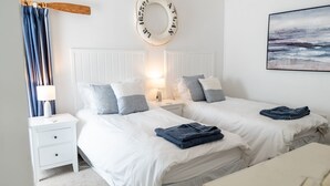 Quarto com duas camas, uma mesa de cabeceira, uma luminária, uma toalha e um objeto decorativo circular na parede.