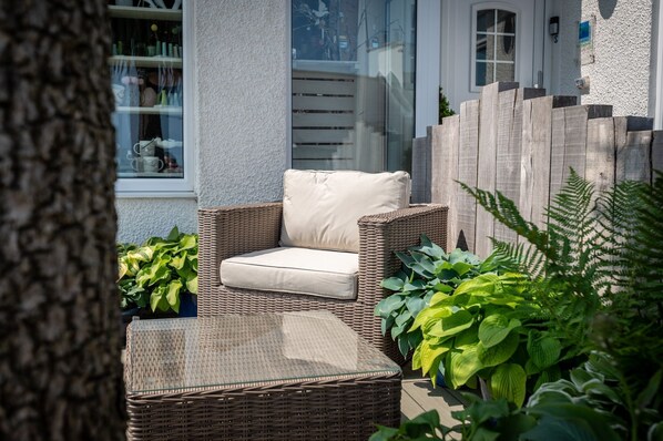 A wicker outdoor seating area with a cushioned chair and a matching ottoman. - Sea Spray - sleeps 4 guests in 2 bedrooms (Moelfre)