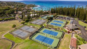 An aerial view of a residential area with multiple tennis courts, a parking lot, and a view of the ocean. - Spacious 2BR Best Ocean Views -Kapalua Golf Villas 11P 5-6 (Lahaina)