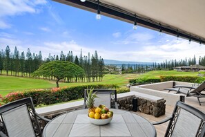 An outdoor seating area with a table, chairs, and a bowl of fruit.