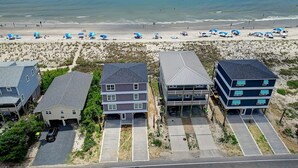 A beachfront property with multiple buildings, including a two-story house with a garage and a larger building with a covered porch.