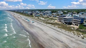 A coastal town with beachfront properties, a pier, and a beach with umbrellas.
