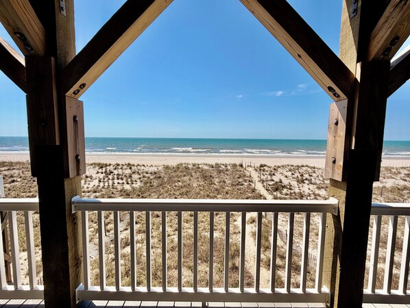 Une terrasse en bois offrant une vue sur une plage et l’océan.