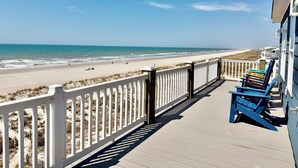 Une terrasse en bois avec une balustrade blanche donnant sur une plage.