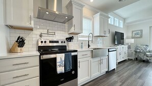 A modern kitchen with white cabinetry, stainless steel appliances, and a wooden floor.