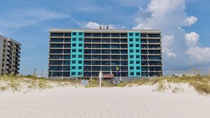 Un hôtel à plusieurs étages au design moderne, doté de balcons et offrant une vue sur la plage.