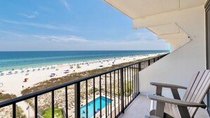 Un balcon avec vue sur une plage et une piscine.