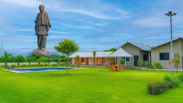 A statue, a swimming pool, and a building with a covered patio.