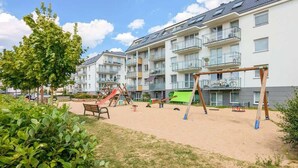 A playground area with swings and a slide, surrounded by apartment buildings.