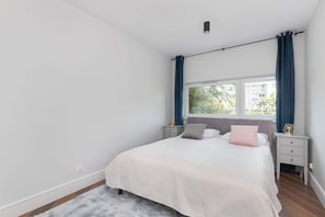 A bedroom with a bed, nightstands, a window, and curtains.