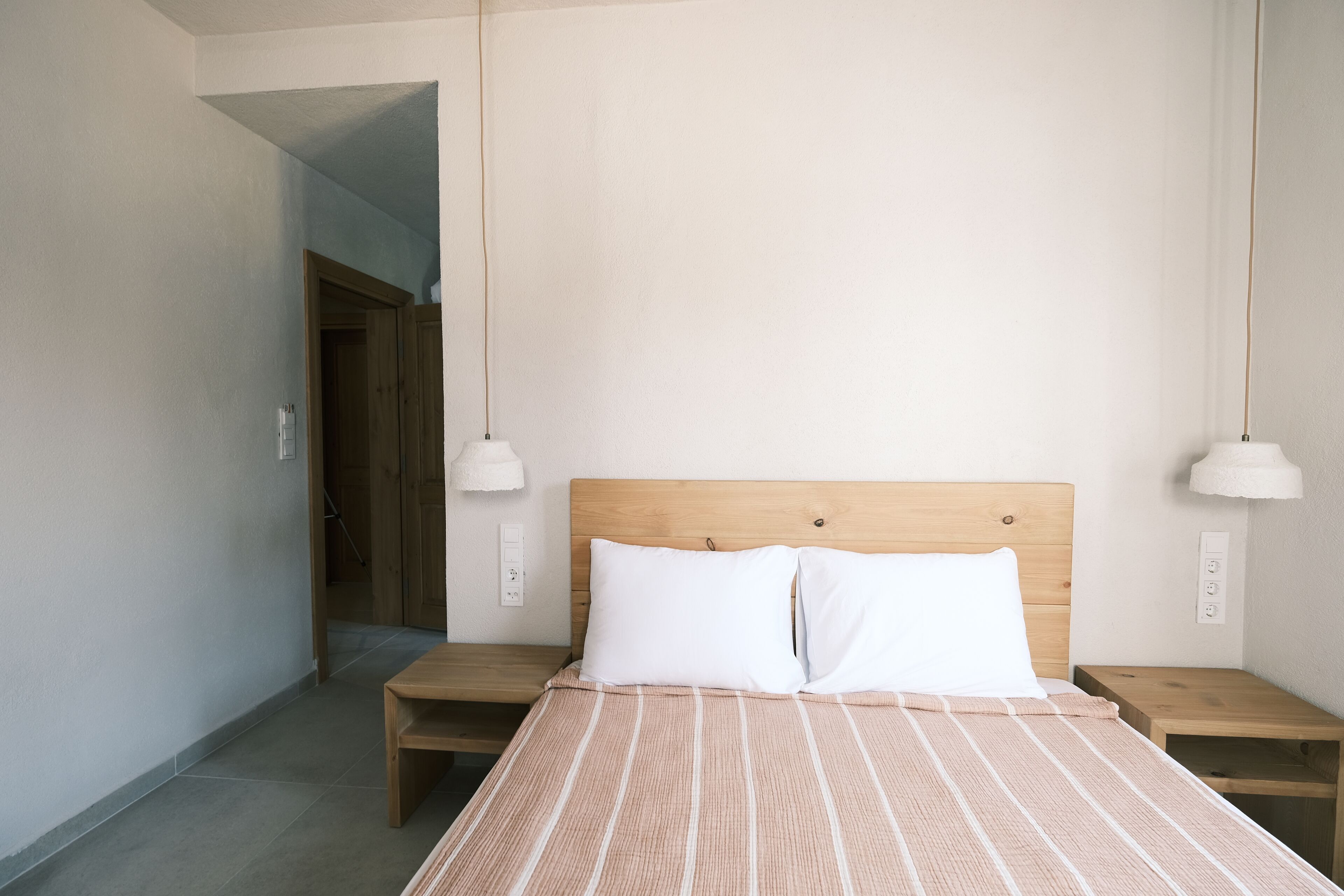 Un dormitorio con una cama de madera, dos mesitas de noche y un aparador.