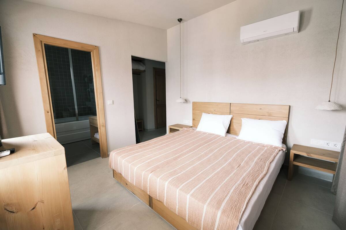 Ein Schlafzimmer mit einem hölzernen Bett, Nachttischen, einem Fernseher und einer Klimaanlage.
