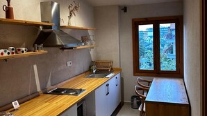 Une cuisine moderne avec des plans de travail en bois, un four encastré et une fenêtre donnant sur un paysage verdoyant.