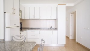 A modern kitchen with white cabinets, a granite countertop, and a built-in dishwasher.